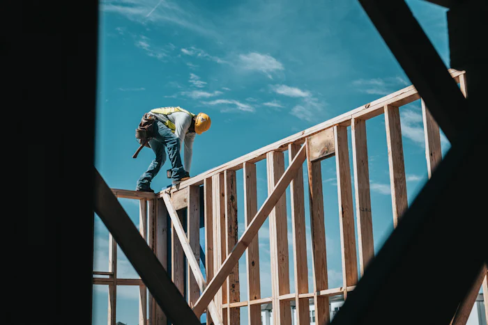 Carpenter in a hard hat standing on top of new wall framing