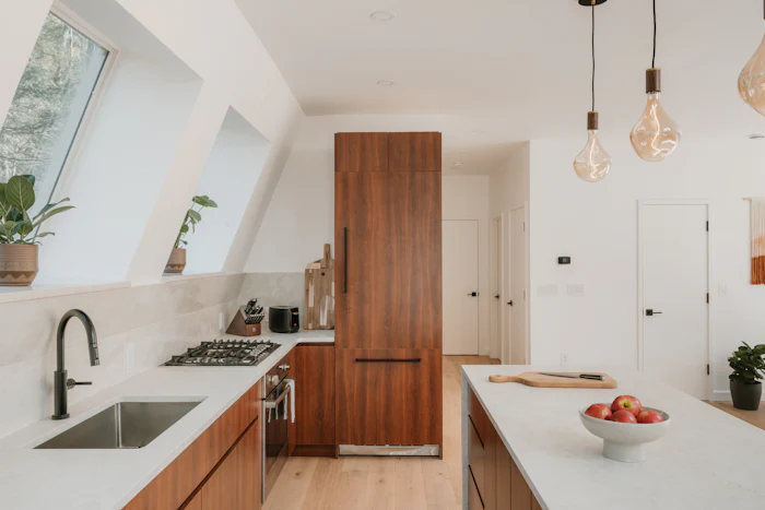 Bright kitchen with walnut cabinets, white counters and pendant lights